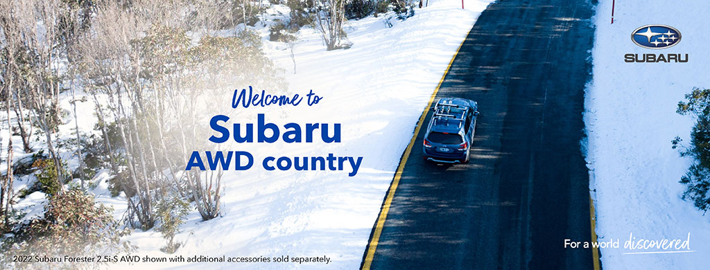 Subaru welcome banner with blue Subaru driving on the road in snowy conditions